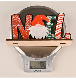 Detailed view of NOEL wooden Christmas gnome ornament on a digital scale weighing 48.6g