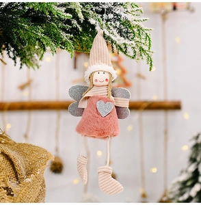 Detail of plush angel ornament with silver wings hanging on a snowy Christmas tree