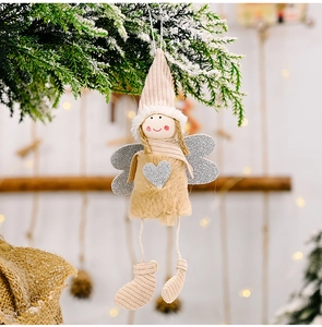 Detail of plush angel ornament with silver heart on snowy Christmas tree branch