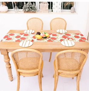 Close-up of a festive Christmas table runner with red poinsettia floral prints on white cloth