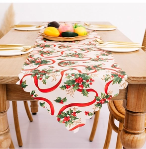 Close-up of Christmas table runner with holly leaves and red ribbon on wooden table