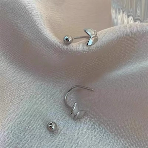 Detail view of silver butterfly stud earrings with screw back on soft pink silk fabric