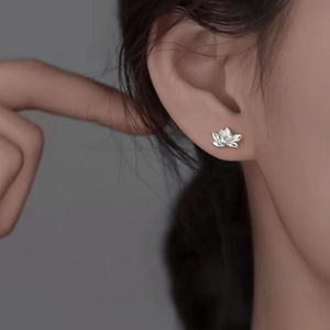 Nahaufnahme eleganter Lotusblumen-Ohrstecker aus Silber am Ohrläppchen