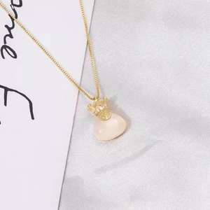 Dettaglio della collana a catena dorata con pendente a sacchetto e pietra di agata bianca