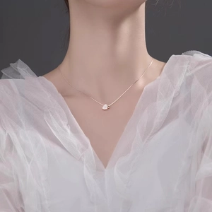 Detail of rose gold heart pendant necklace with shimmering pave diamonds on a model