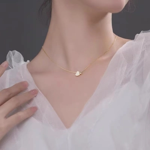 Elegant gold heart pendant necklace with sparkling pavé crystals worn on collarbone