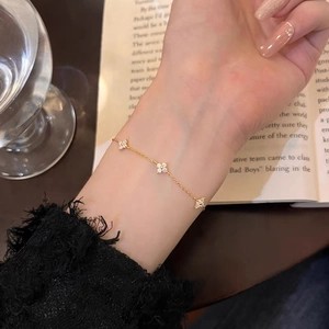 Detail of a gold four-leaf clover bracelet with sparkling zircons worn on a wrist