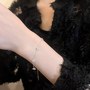 Detail of silver clover bracelet featuring sparkling zircons on a female model's wrist