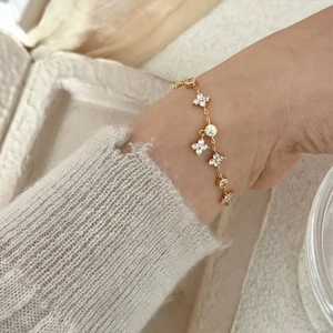 Close-up of a gold clover bracelet with sparkling zircons worn on a female wrist