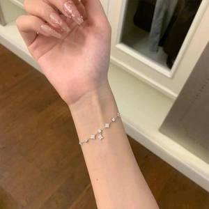 Detail of silver clover bracelet with sparkling zircons worn on the wrist for elegance