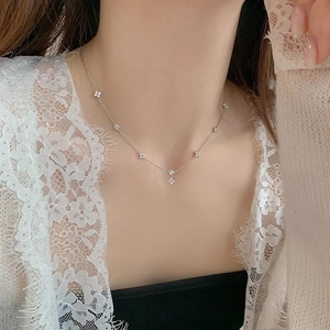 Detail of silver clover necklace with zircon charms on a delicate O-chain