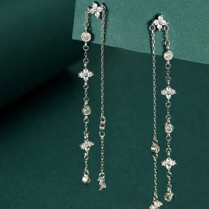 Elegant long tassel earrings with clover motif and zircons on deep green background