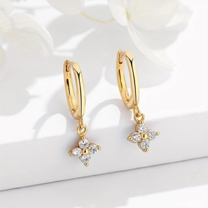 Macro shot of 18K gold earrings with four-petal flowers and cubic zirconia accents