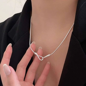 Close-up of a silver snake chain necklace with a unique fish hook clasp on a model