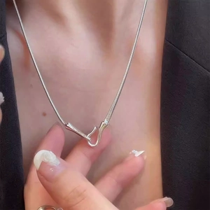 Detail of silver snake chain necklace with abstract hook clasp worn on black blazer