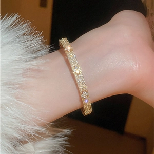 Luxurious gold clover bangle with white zircon pavé setting on a soft fur background