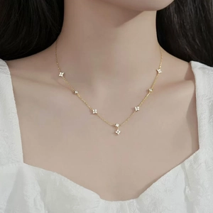 Elegant gold four-leaf flower necklace with zircon charms on a model wearing white