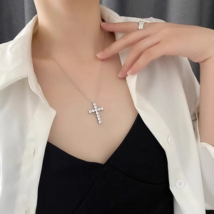 Collier avec pendentif croix étincelant en argent porté par un modèle sous lumière douce