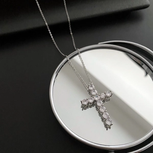 Gros plan détaillé d'un collier croix serti de zircons reflété sur un miroir circulaire