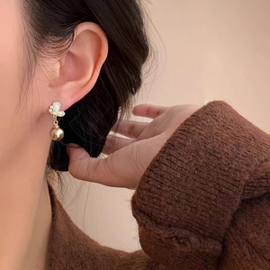 Detailed close-up of champagne butterfly drop earrings with pearls on a model