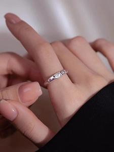 Macro detail of silver flower ring with pink crystals and black enamel on model's hand