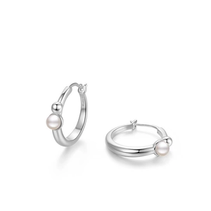 Detailed close-up of silver hoop earrings with round white pearls and small metal beads