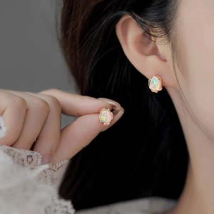 Macro detail of oval opal earrings in rose gold setting with delicate scalloped edges