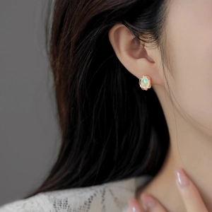 Close-up of a French vintage rose gold earring with oval opal stone on model ear
