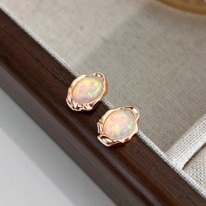 Detailed close-up of vintage oval opal earrings with rose gold textured metal base