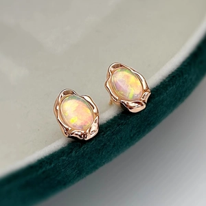 Vintage rose gold opal earrings set on a dark green velvet jewelry box with retro texture