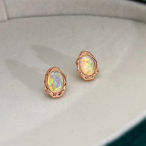 Close-up of vintage oval opal earrings with rose gold textured frames in a jewelry box