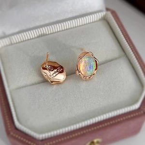 Close-up of irregular rose gold opal earrings with iridescent stones and textured finish