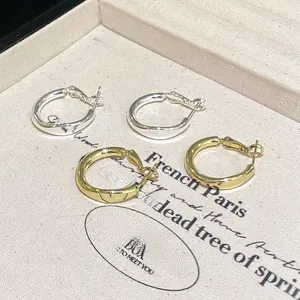 Créoles polies en or et argent présentées sur un plateau à bijoux texturé de luxe