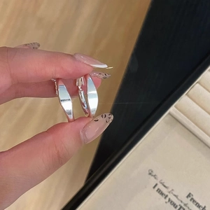 Gros plan de boucles d'oreilles créoles larges et plates en argent avec fini poli brillant