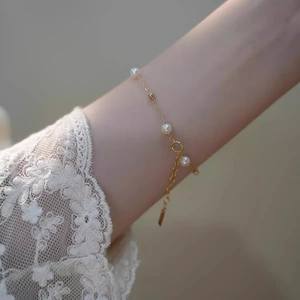 Elegant gold pearl bracelet with adjustable chain and three white pearls on a model wrist