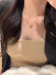 Gros plan détaillé d'un collier trèfle doré avec zircons blancs porté par un mannequin
