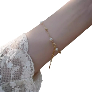 Elegant gold chain bracelet with small white pearls on woman wrist with lace sleeve
