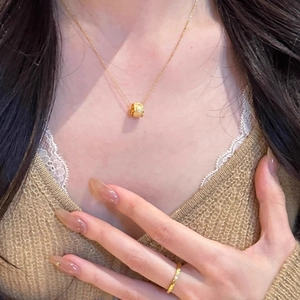 Golden barrel pendant necklace and textured ring set worn on an elegant sweater