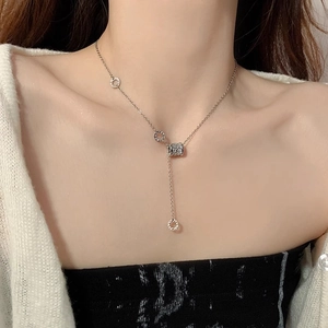 Primo piano di una collana minimalista argento con pendente a cilindro sul collo