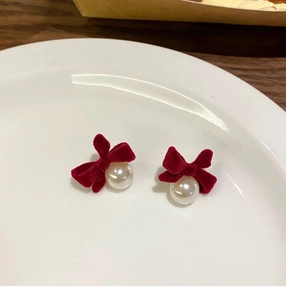 Detail of vintage velvet bow earrings with lustrous white pearls on a ceramic plate