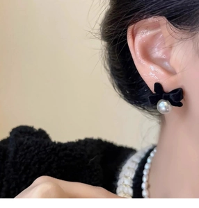 Detail of French vintage velvet bow earrings with a white pearl drop worn by a model