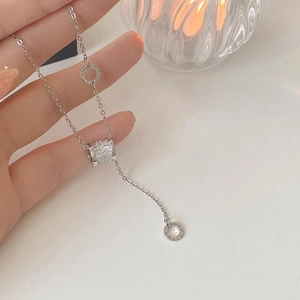 Dettaglio della collana d'argento con anelli a numeri romani e ciondolo in zircone lucido
