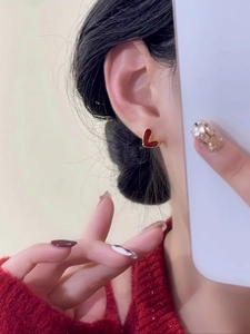Gros plan d'un mannequin portant des boucles d'oreilles cœur en émail bordeaux et or