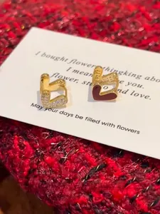 Détail de boucles d'oreilles cœur double face avec émail rouge et cristaux brillants
