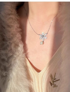 Close-up of snowflake pendant with zircon crystals and round pearl on silver chain