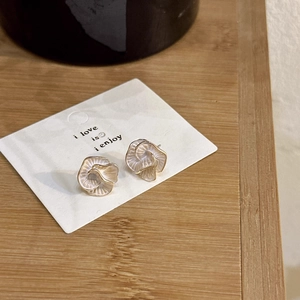 Detail of cream white camellia earrings with gold edges on a wooden tray display