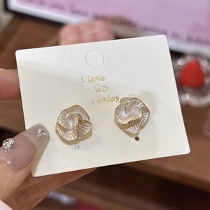 Macro detail of French vintage camellia stud earrings with cream enamel and gold edges