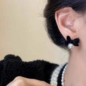 French vintage velvet bow earrings with white pearls worn on a model in close-up view
