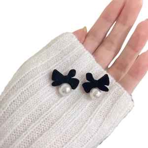 French vintage velvet bow earrings with white pearl pendants worn on a white sweater