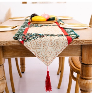Details eines Weihnachts-Tischläufers aus Jacquard-Stoff mit Tannenbäumen und roten Quasten